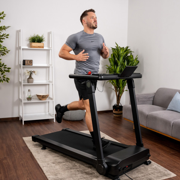 Eine Person in sportlicher Kleidung trainiert auf dem Kettler Laufband Track 200 in einem Wohnzimmer.
